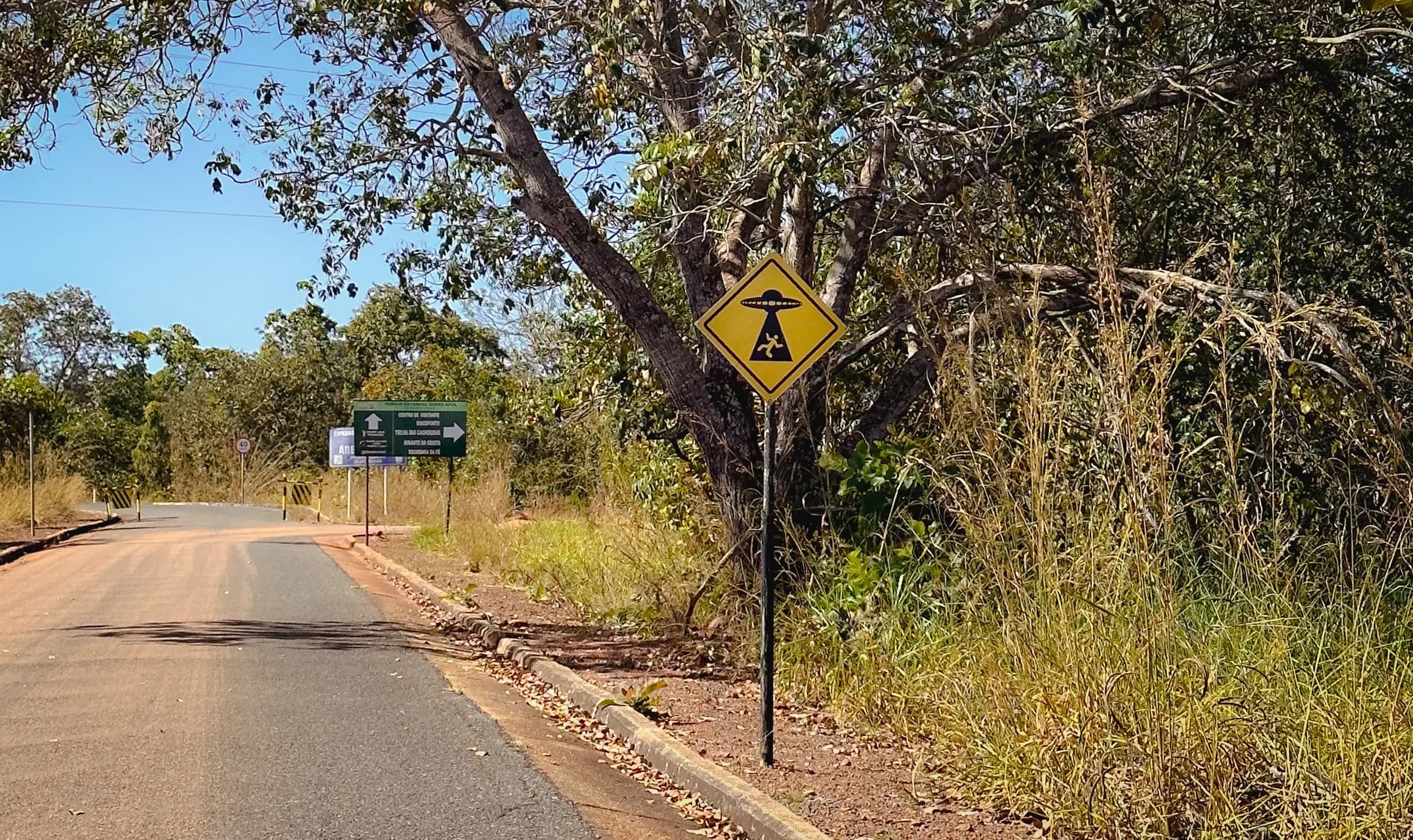 Placa amarela triangular com a representação de alguém sendo abduzido